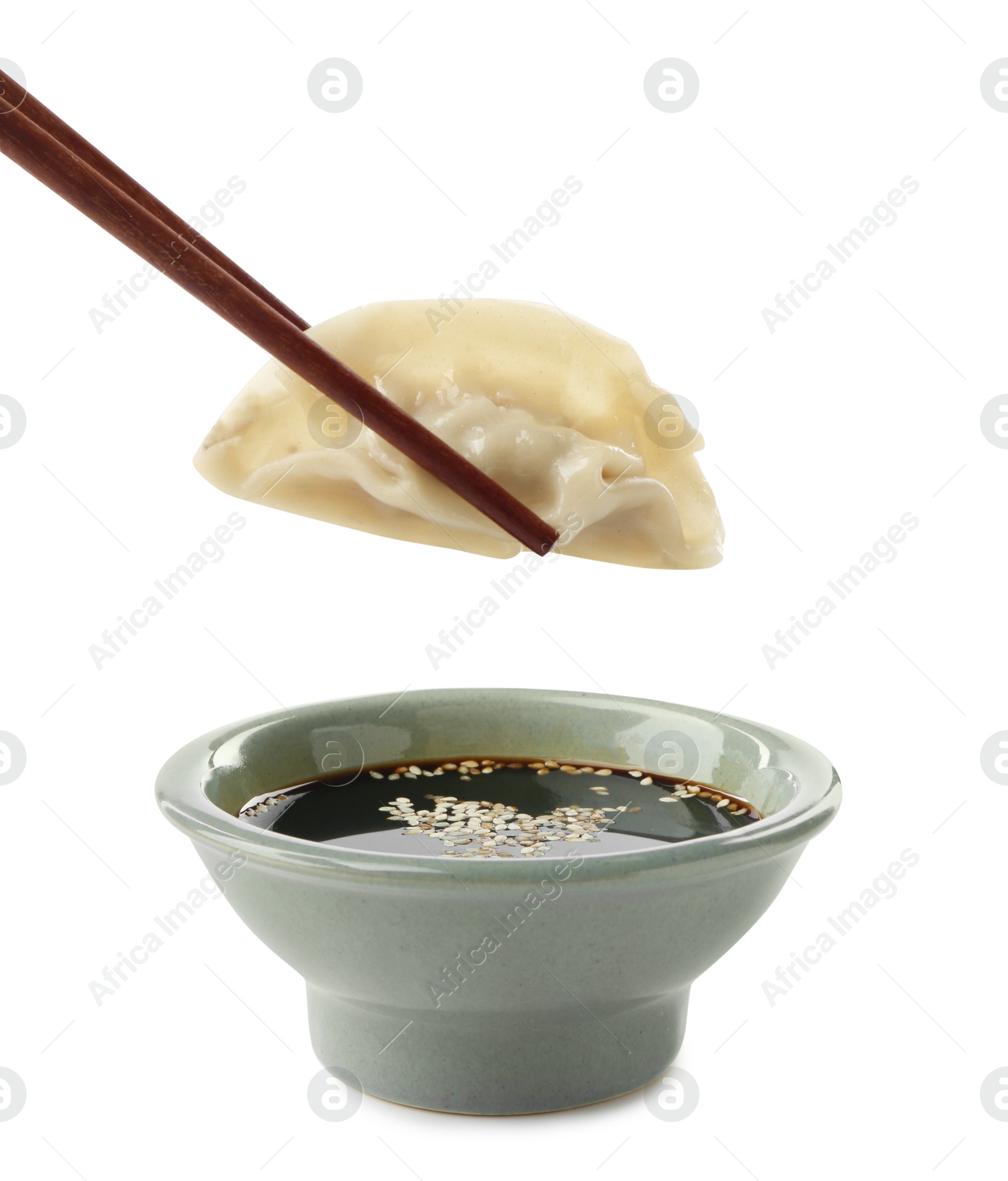 Photo of Dipping tasty gyoza (dumpling) into soy sauce on white background