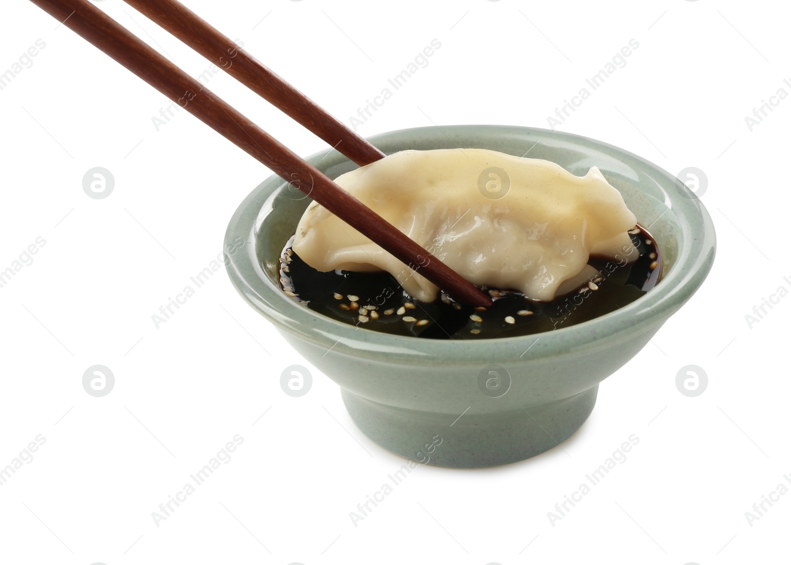 Photo of Dipping tasty gyoza (dumpling) into soy sauce on white background