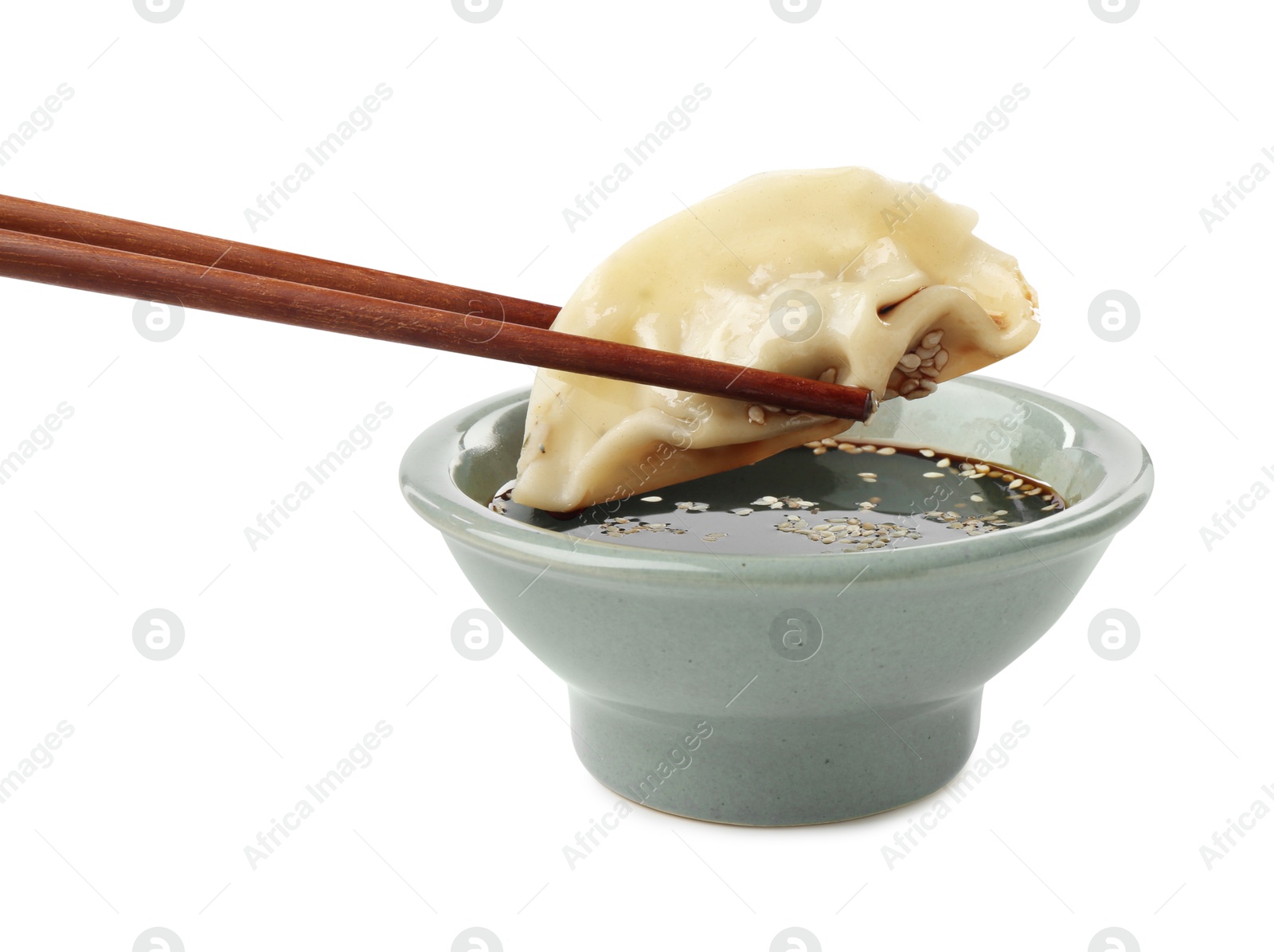 Photo of Dipping tasty gyoza (dumpling) into soy sauce on white background