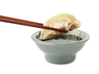 Photo of Dipping tasty gyoza (dumpling) into soy sauce on white background