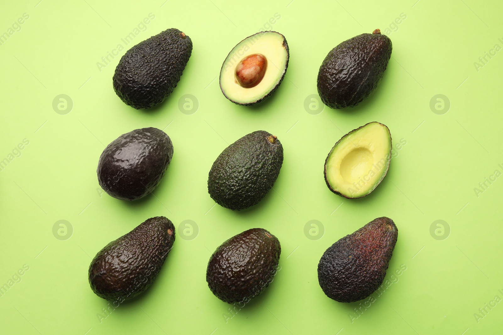 Photo of Fresh ripe avocados on light green background, flat lay