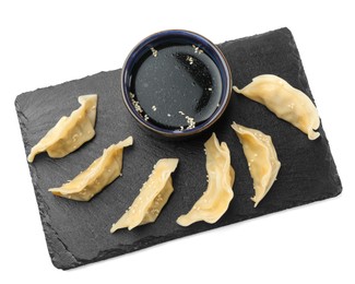 Photo of Tasty boiled gyoza (dumplings) with soy sauce on white background, top view