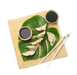 Photo of Tasty boiled gyoza (dumplings) with soy sauce, chopsticks and sesame on white background, top view