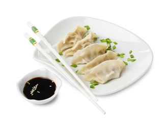 Photo of Tasty boiled gyoza (dumplings) with green onion, soy sauce and chopsticks on white background