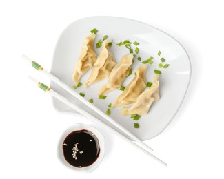 Photo of Tasty boiled gyoza (dumplings) with green onion, soy sauce and chopsticks on white background, top view