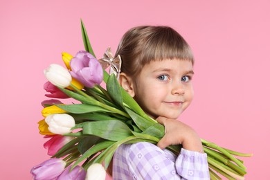 Photo of Cute little girl with bouquet of tulips on pink background