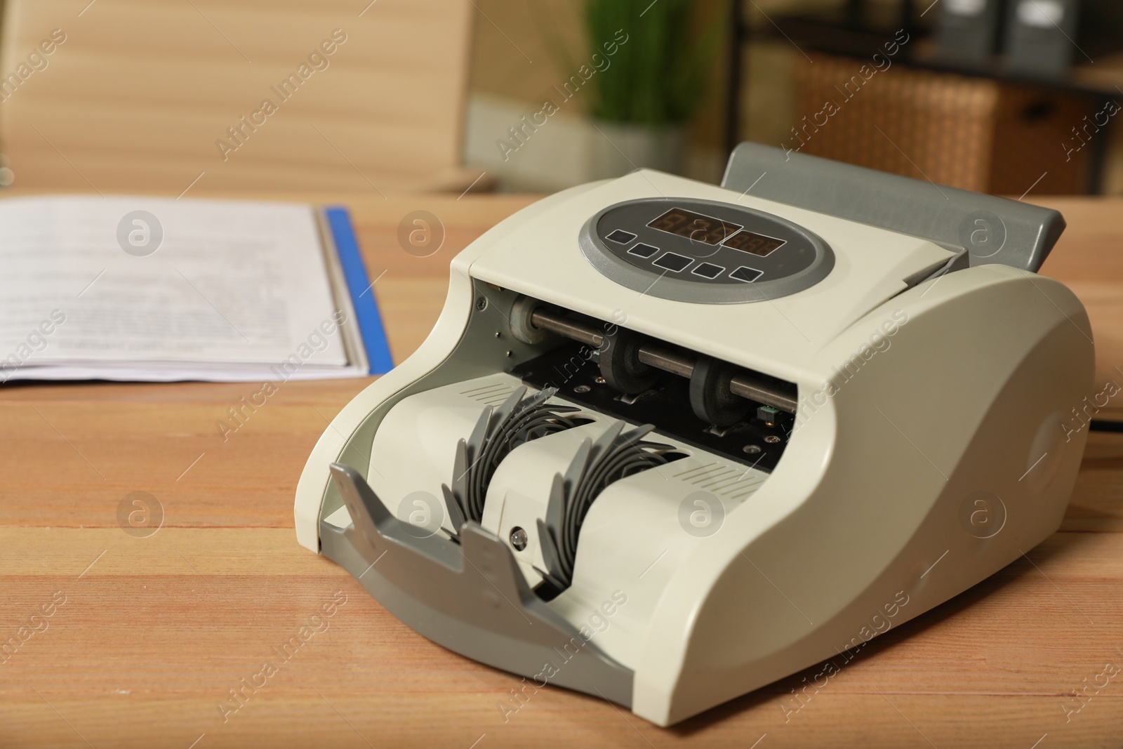 Photo of Modern banknote counter on wooden table indoors