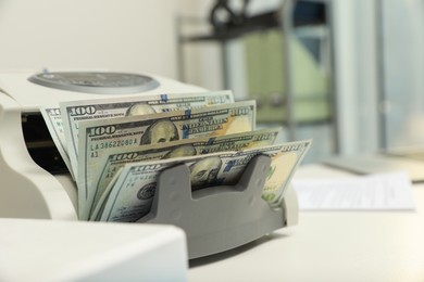 Photo of Modern banknote counter with money on white table indoors, closeup