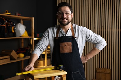 Photo of Professional repairman with wooden stool and tool in workshop