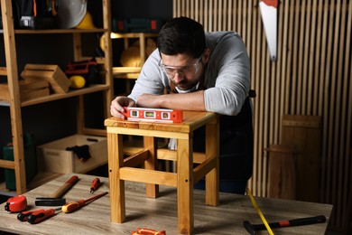 Photo of Repairman checking stool level at table in workshop