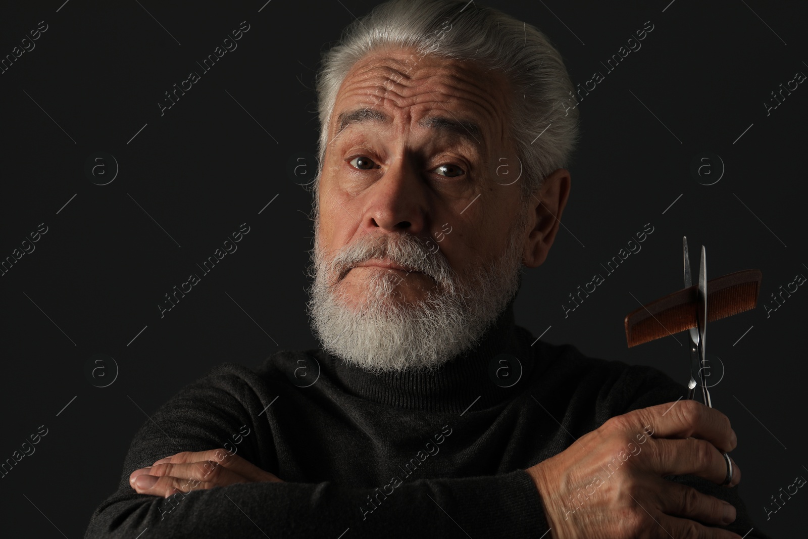 Photo of Bearded man with scissors and comb on dark grey background