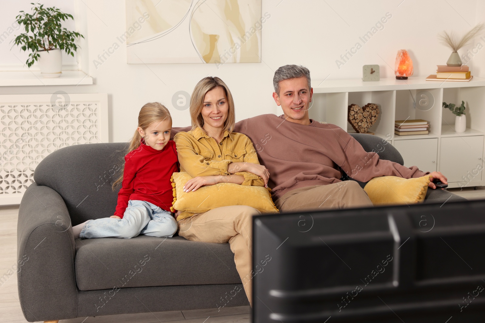 Photo of Family watching TV on sofa at home