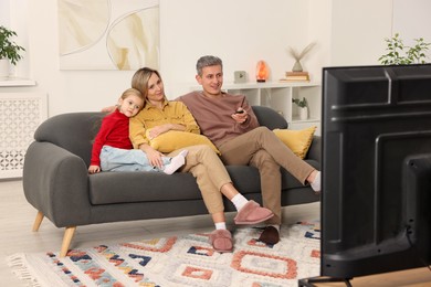 Photo of Family watching TV on sofa at home