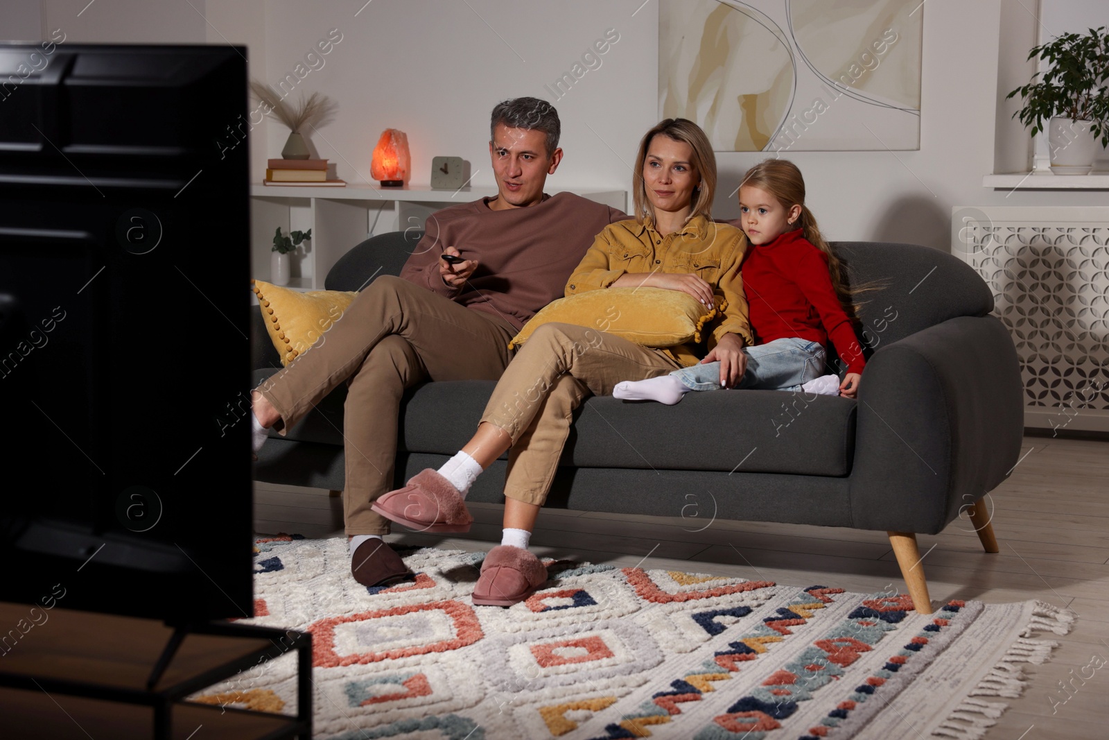 Photo of Family watching TV on sofa at home