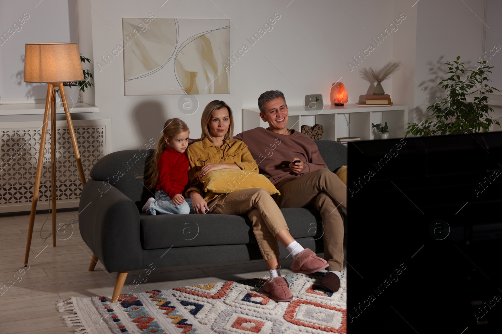 Photo of Family watching TV on sofa at home