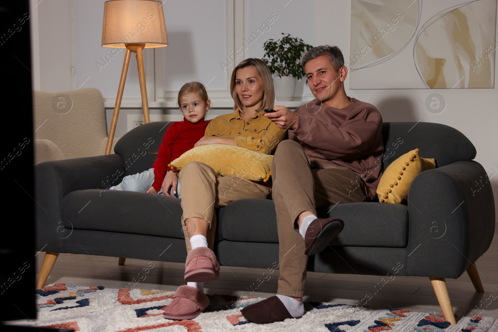 Photo of Family watching TV on sofa at home