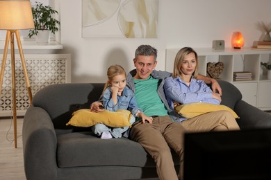 Family watching TV on sofa at home