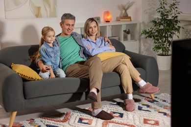 Photo of Family watching TV on sofa at home