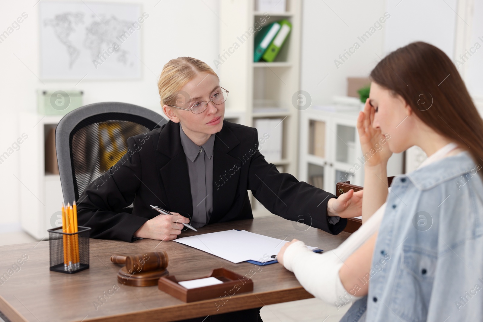 Photo of Injured woman having meeting with lawyer in office, selective focus