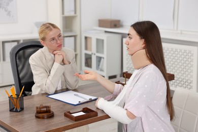 Photo of Injured woman having meeting with lawyer in office, selective focus