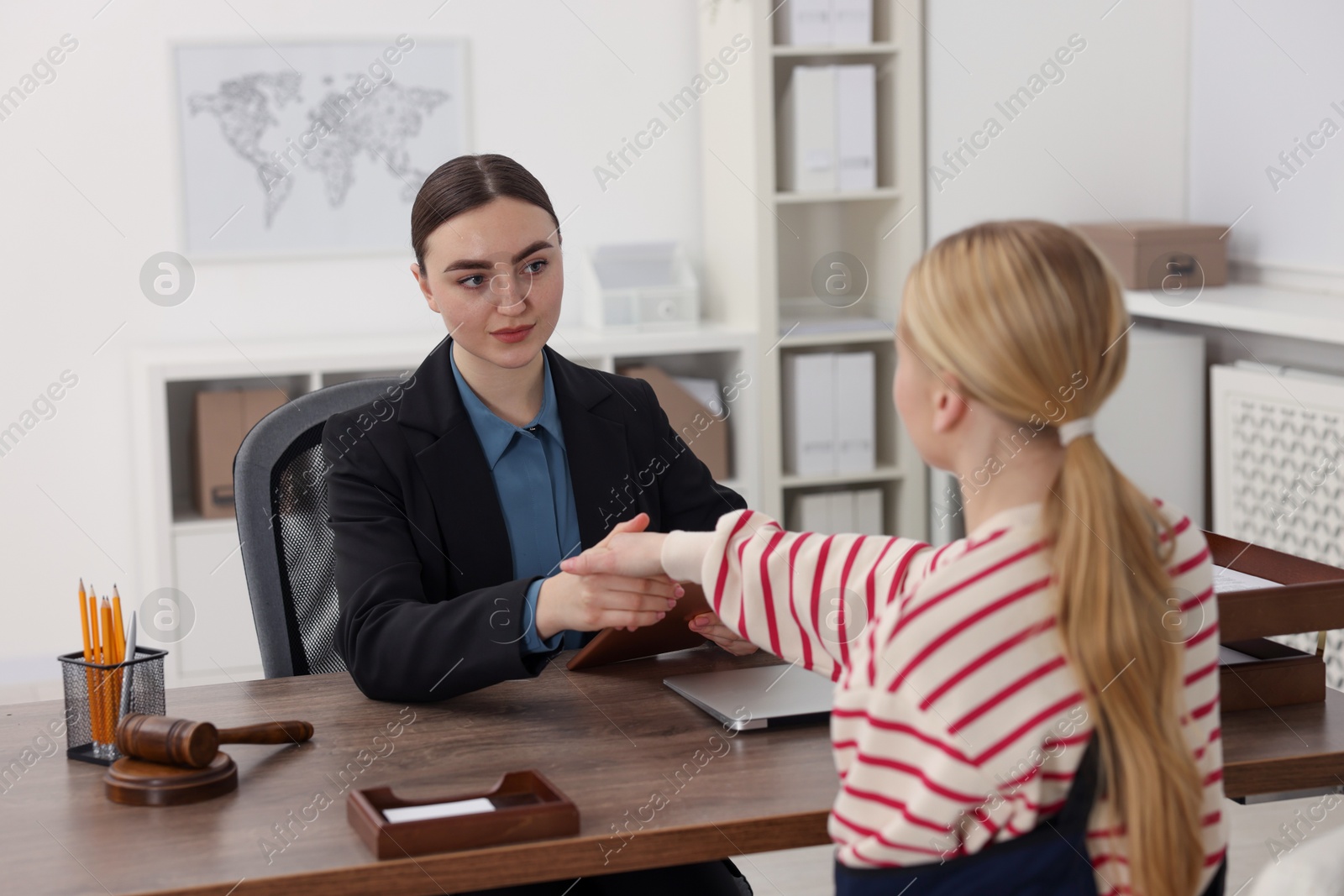 Photo of Injured woman and lawyer shaking hands in office, selective focus