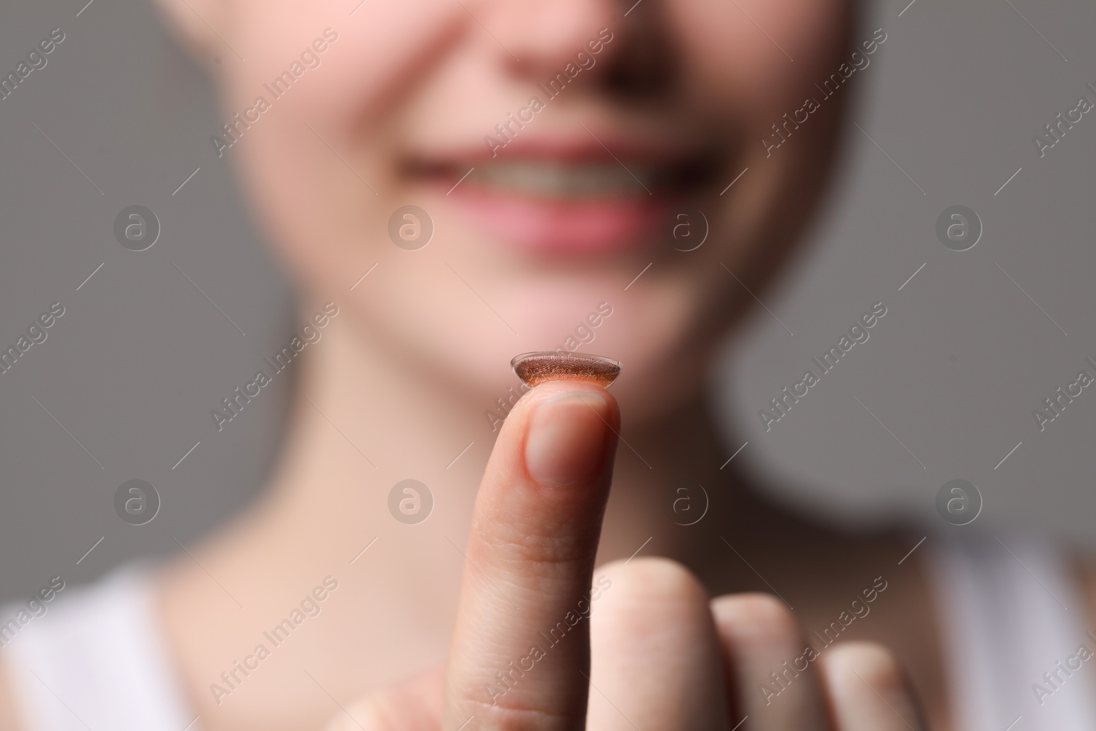 Photo of Woman with color contact lens on grey background, closeup. Selective focus