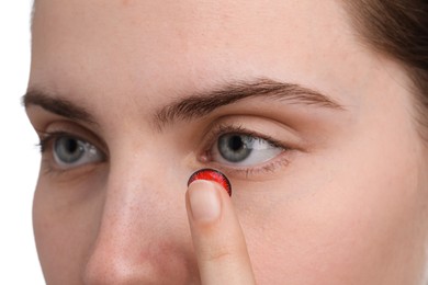 Photo of Woman putting in red color contact lens on white background, closeup