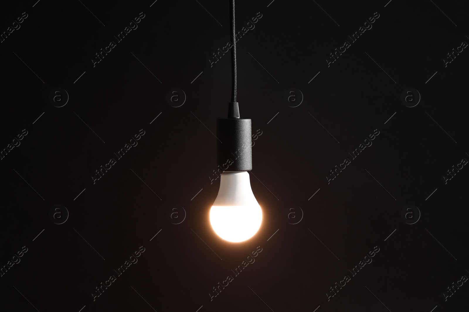 Photo of Glowing light bulb hanging on dark background