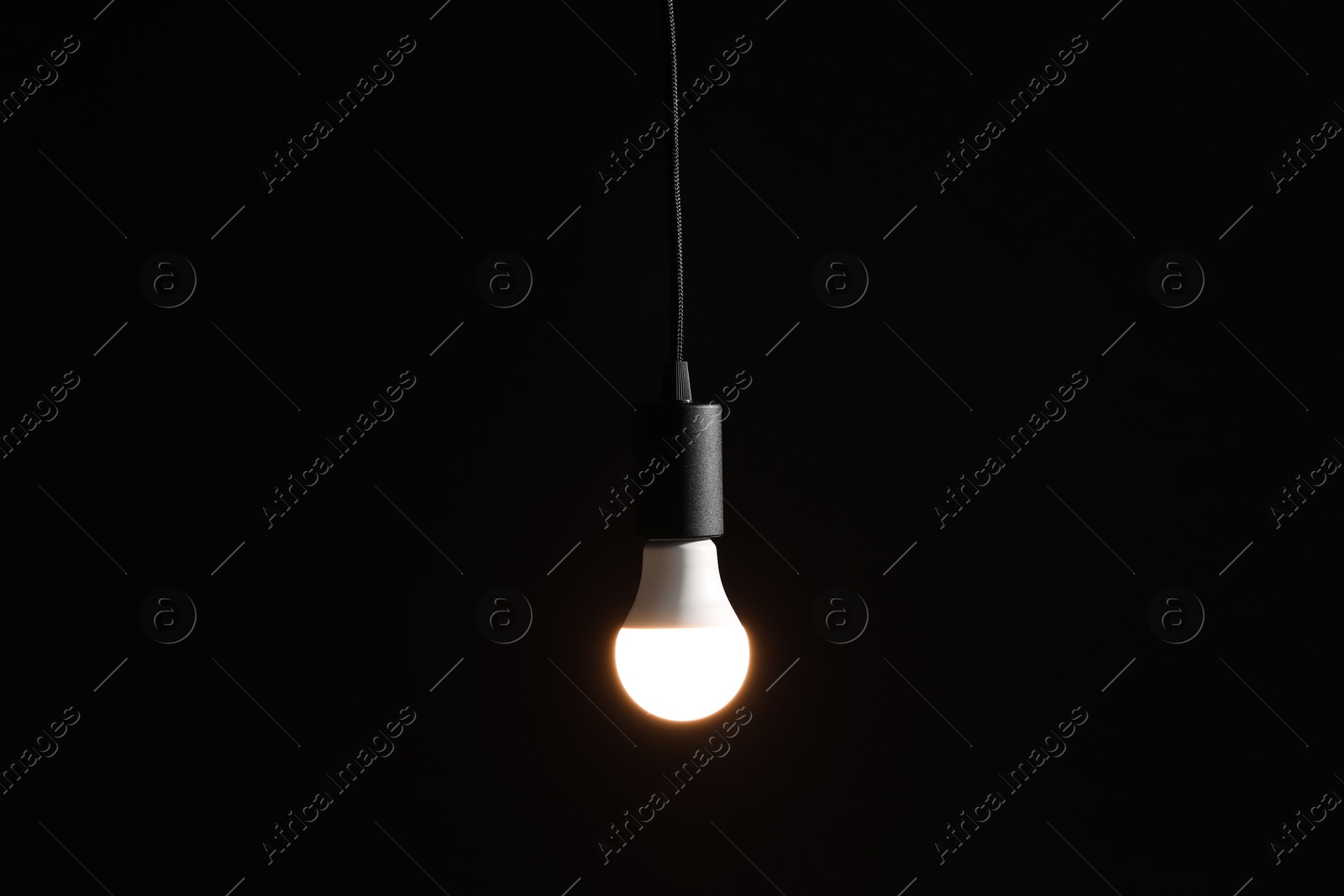 Photo of Glowing light bulb hanging on dark background