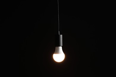 Photo of Glowing light bulb hanging on dark background