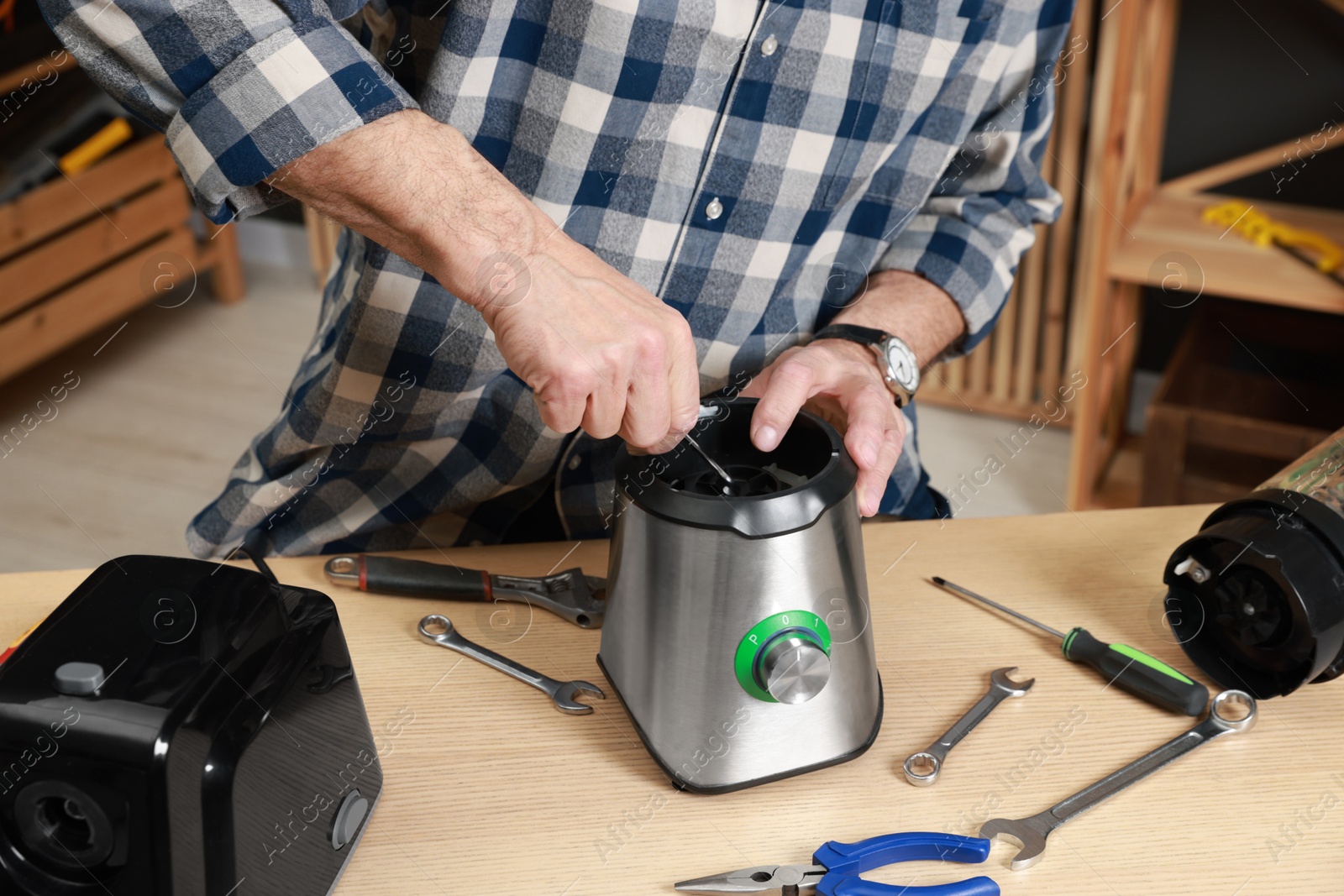 Photo of Relaxing hobby. Senior man repairing blender with wrench in workshop, closeup