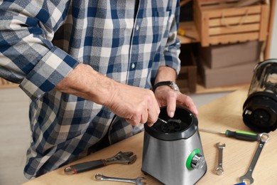 Photo of Relaxing hobby. Senior man repairing blender with wrench in workshop, closeup