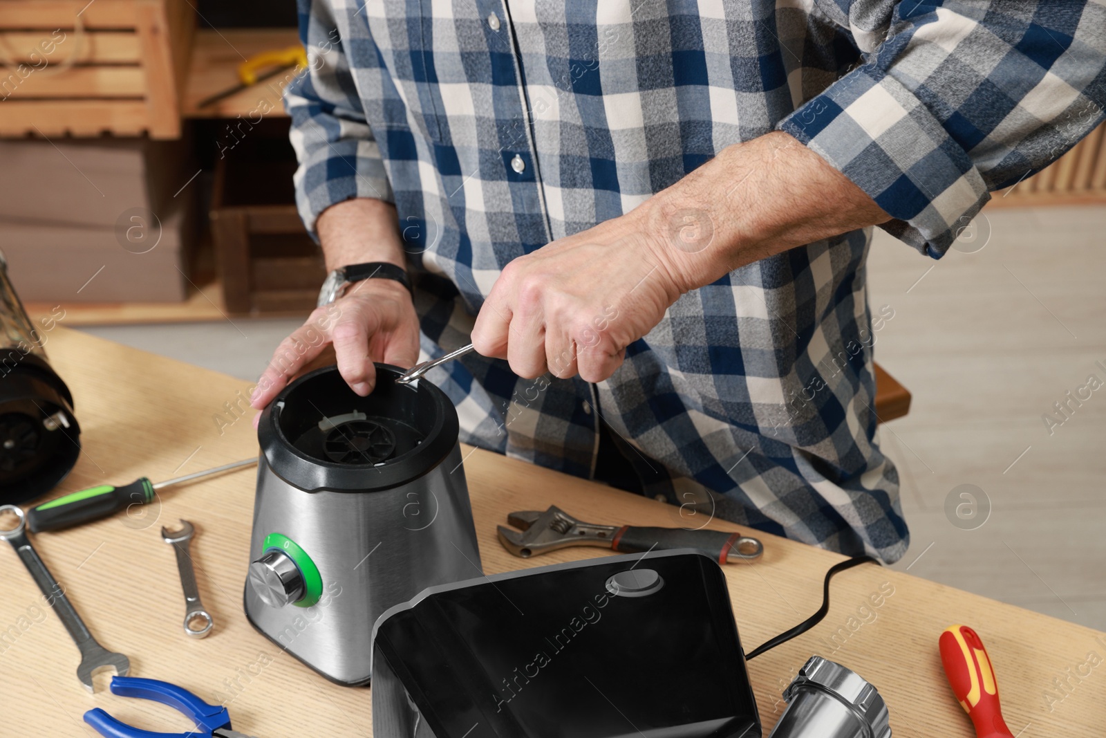 Photo of Relaxing hobby. Senior man repairing blender with wrench in workshop, closeup