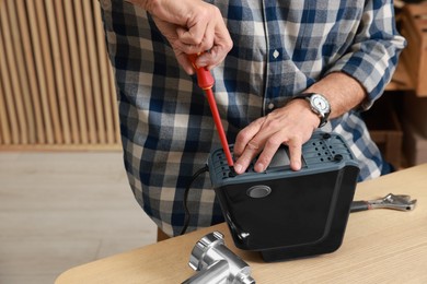 Photo of Relaxing hobby. Senior man repairing meat grinder with screwdriver in workshop, closeup