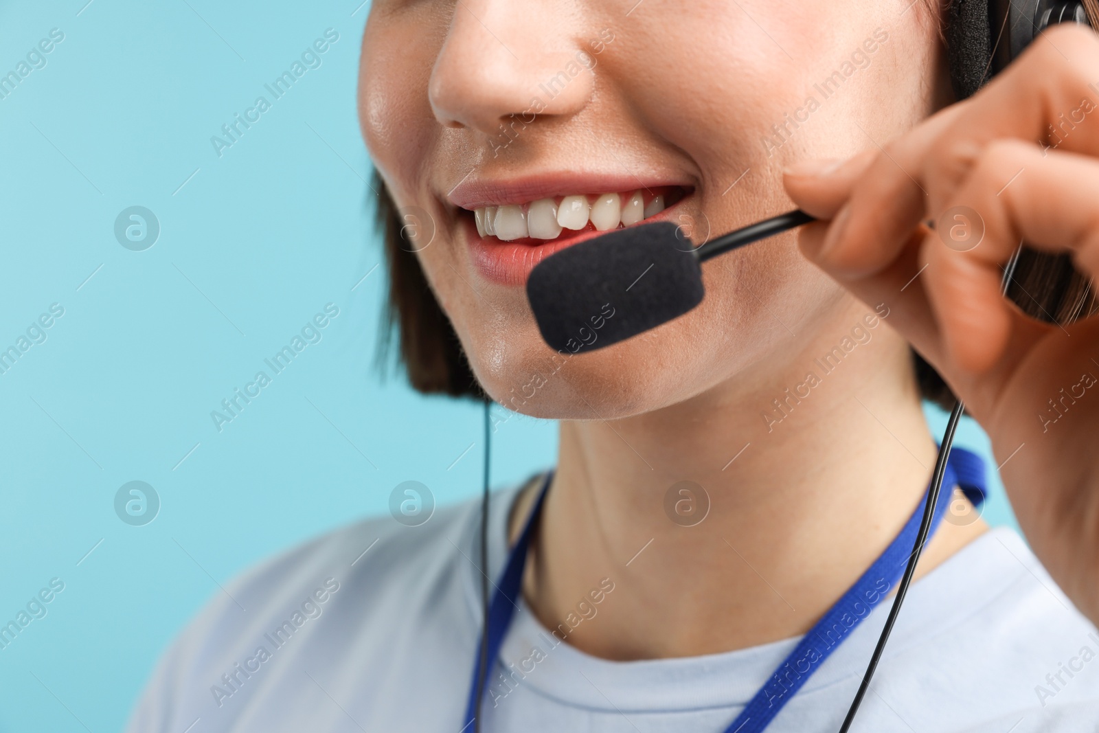 Photo of Technical support call center. Smiling operator on light blue background, closeup