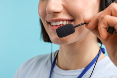 Photo of Technical support call center. Smiling operator on light blue background, closeup