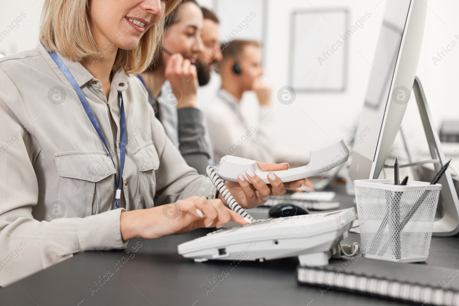 Photo of Technical support call center. Team of operators working at table in office, closeup