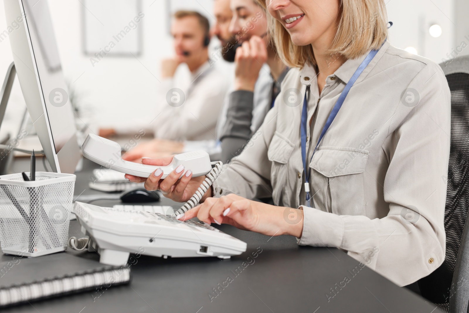 Photo of Technical support call center. Team of operators working at table in office, closeup