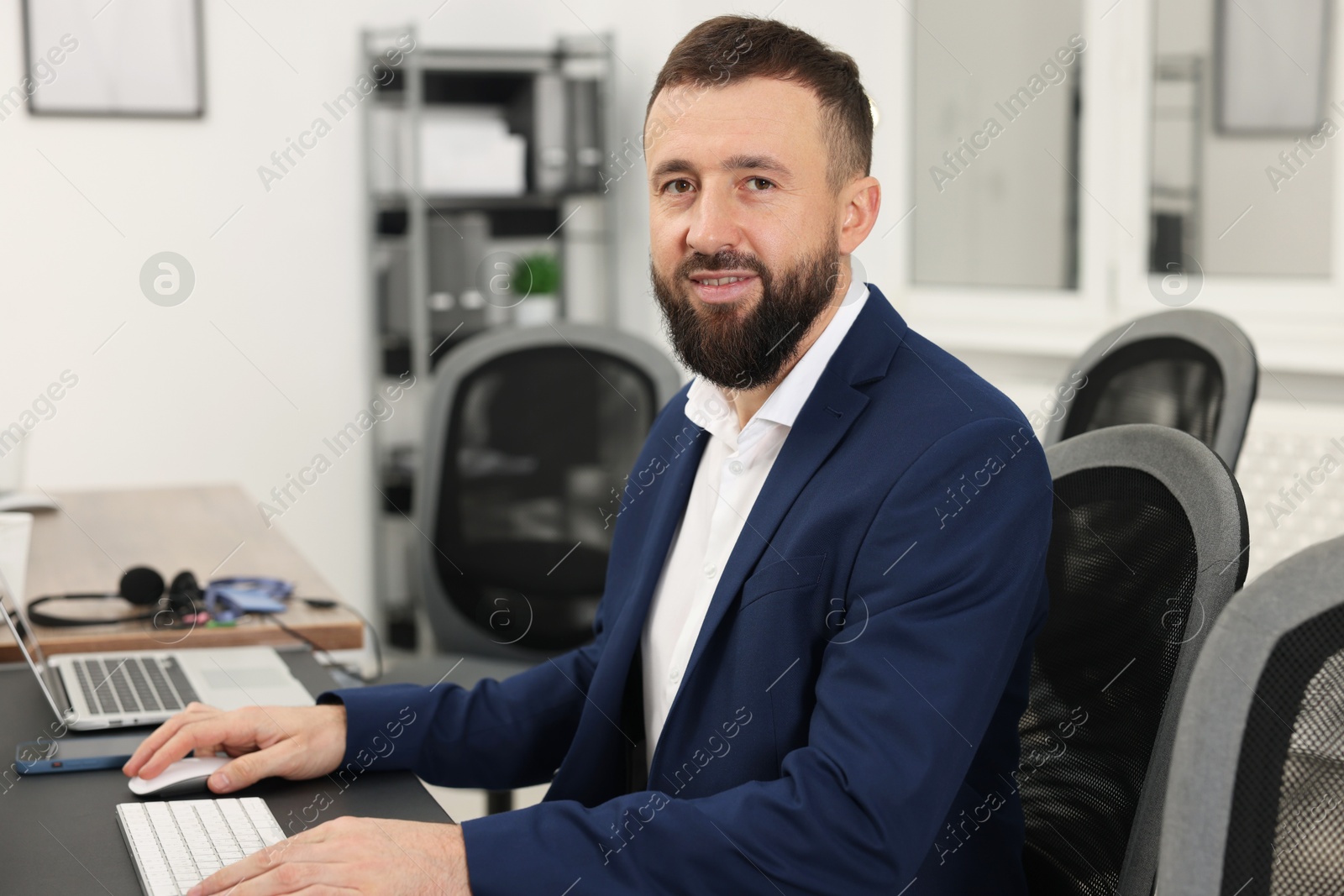 Photo of Technical support call center. Smiling operator working at table in office