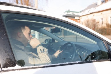 Photo of Sleepy driver yawning in his modern car, view from outside