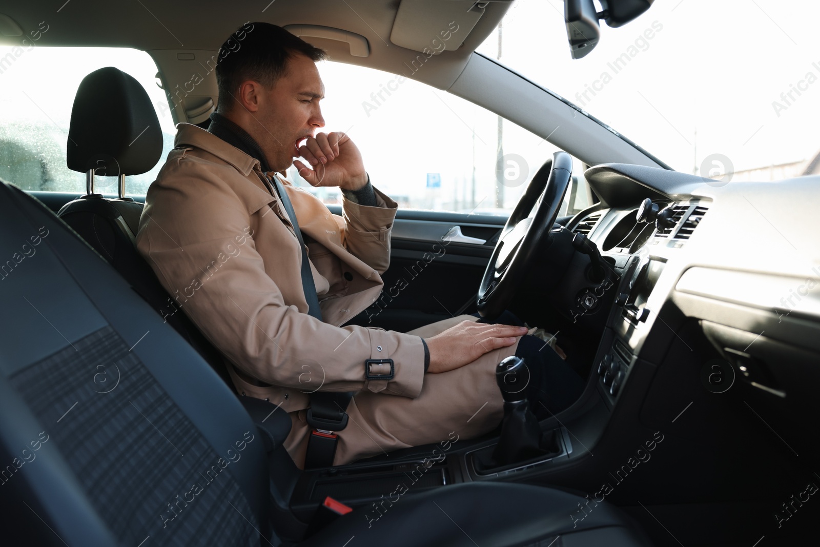 Photo of Sleepy driver yawning in his modern car