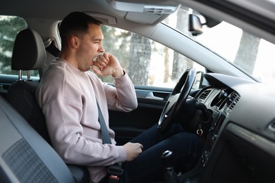 Photo of Sleepy driver yawning in his modern car