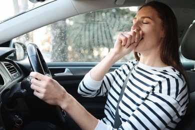 Photo of Sleepy driver yawning in her modern car