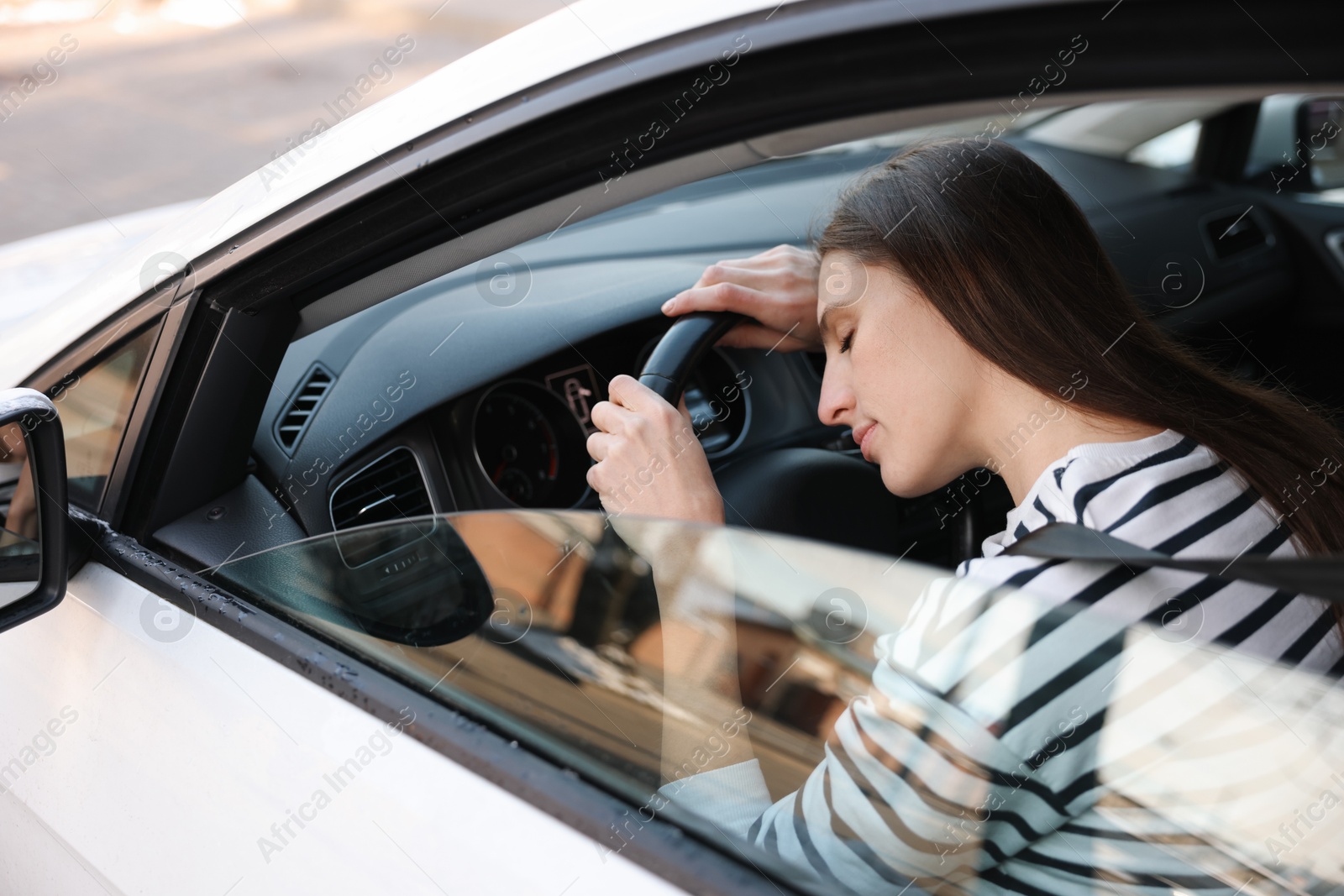 Photo of Tired driver sleeping on steering wheel in car, view from outside