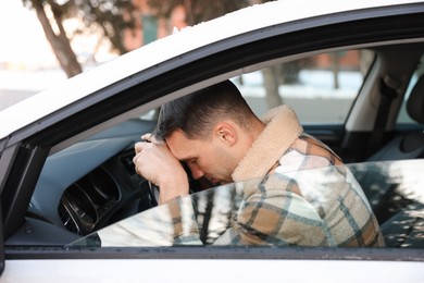 Photo of Tired driver sleeping on steering wheel in car, view from outside