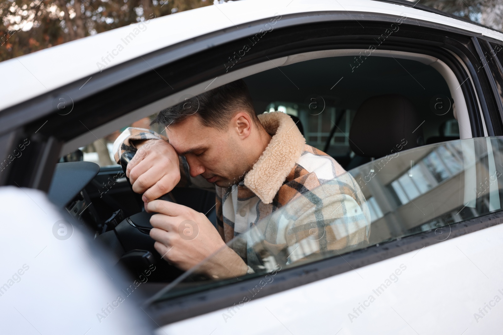 Photo of Tired driver sleeping on steering wheel in car, view from outside