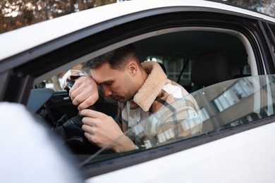 Photo of Tired driver sleeping on steering wheel in car, view from outside