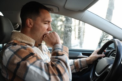 Photo of Sleepy driver yawning in his modern car