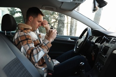 Photo of Sleepy driver with glasses in his modern car