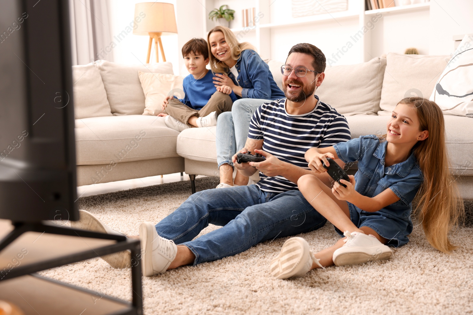 Photo of Happy family playing video games in living room